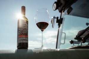 Flasche Rotwein Neusiedlersee DAC Zweigelt steht neben einem Rotweinglas auf einem Traktor und die Sonne scheint durch die Flasche